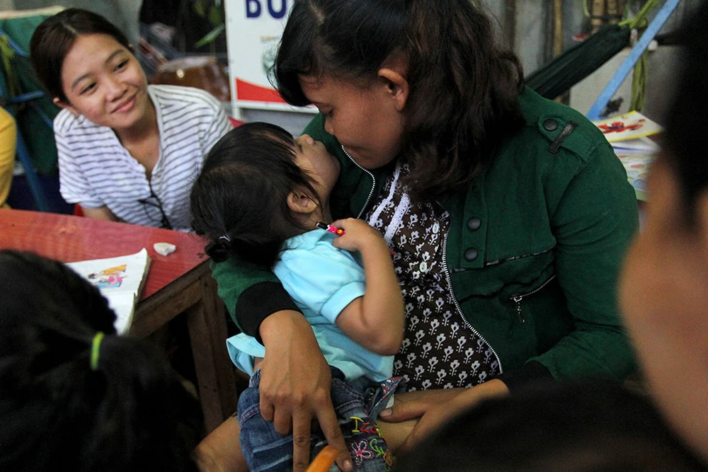 Mẹ nuôi Thị Liên và bé Ngọc Yến đùa giỡn với nhau trong buổi cơm tối. Ảnh: HOÀNG GIANG