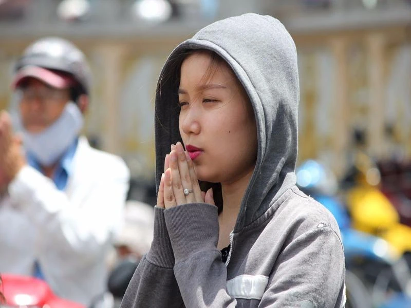 Cô gái đội nắng cầu nguyện trước tượng Quan Âm