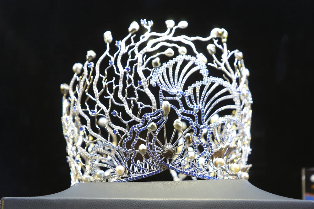 Trên nền chất liệu vàng trắng, từng chi tiết của vương miện được cộng hưởng thêm ánh sáng lấp lánh nhờ 1.000 viên kim cương tự nhiên cùng 12 viên ngọc Tahiti ánh xà cừ đen huyền ảo và những viên ngọc trai sắc trắng tinh khôi bao quanh.