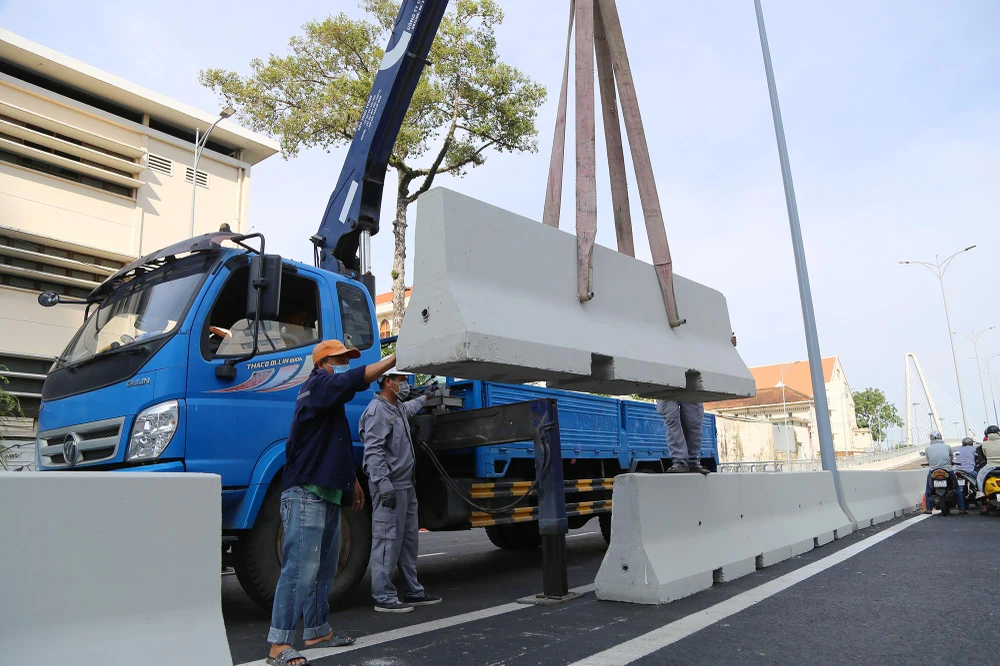 Công nhân lắp đặt những tấm bê tông cuối cùng ngăn 2 làn cầu phía quận 1 trước giờ cho dân lưu thông.