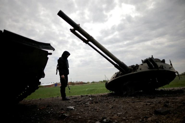 Một quân nhân Ukraine kiểm tra một chiếc xe bọc thép bị phá hủy của Nga ở vùng Zaporizhzhia, Ukraine. Ảnh: REUTERS