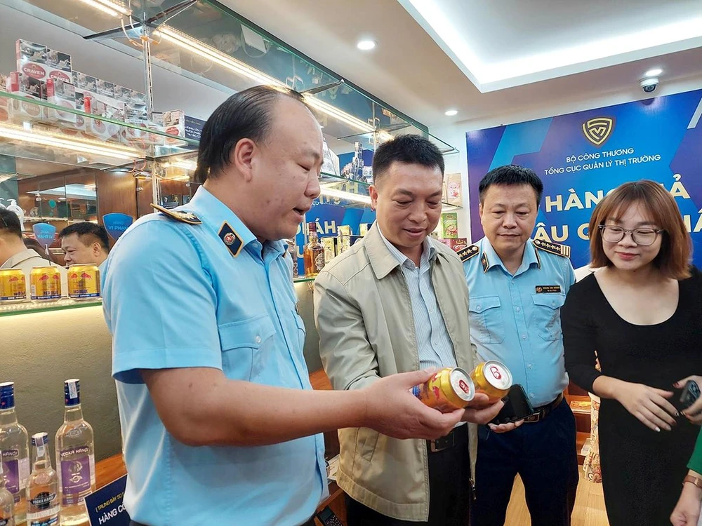 Tổng cục trưởng Tổng cục Quản lý thị trường Trần Hữu Linh (ngoài cùng bên trái) hướng dẫn cách phân biệt hàng thật với hàng vi phạm. (Ảnh: AH)