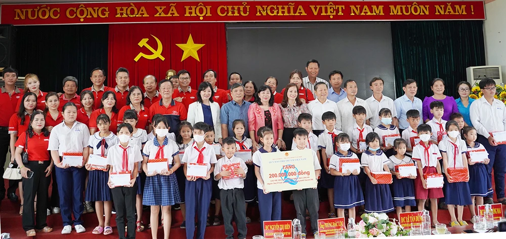 Đại diện đơn vị nhà tài trợ chụp hình lưu niệm với các em học sinh.
