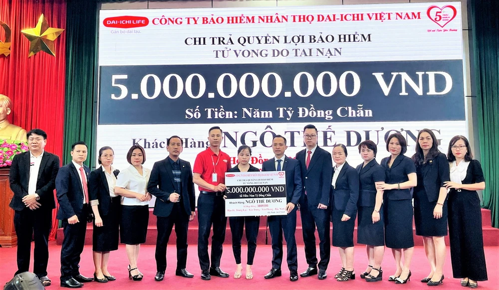 Ông Tạ Văn Thái, Giám đốc Cấp cao Kinh doanh miền Bắc, Dai-ichi Life Việt Nam (thứ 7, phải qua) trao biểu trưng số tiền 5 tỷ đồng chi trả quyền lợi bảo hiểm cho gia đình khách hàng.
