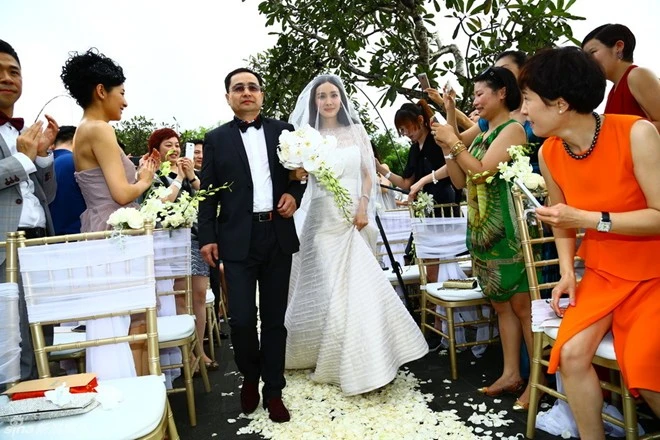 Cô dâu được cha dẫn vào lễ đường trên con đường rải hoa trắng.