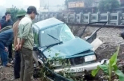 Ô tô bị biến dạng, nằm cạnh đường ray, tài xế và một người trong xe bị thương nặng. Ảnh: Sơn Dương