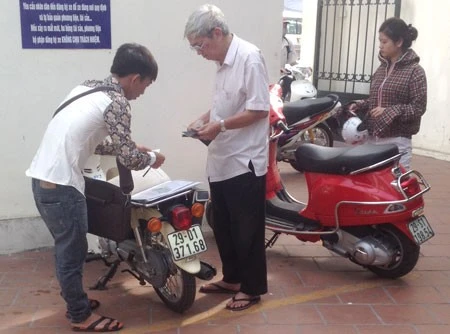 Một “cò” (ngoài cùng, bên trái) đang giao dịch với khách tại điểm đăng ký Hai Bà Trưng, Hà Nội.