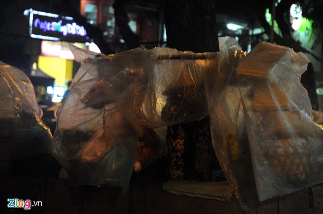 Trời mưa khiến việc buôn bán cũng trở nên khó khăn, ế ẩm hơn ngày thường. Trong ảnh: Người phụ nữ bán hang rong trên đường Nguyễn Văn Cừ (quận 5) đang ngồi trong mưa chờ khách mua hang.