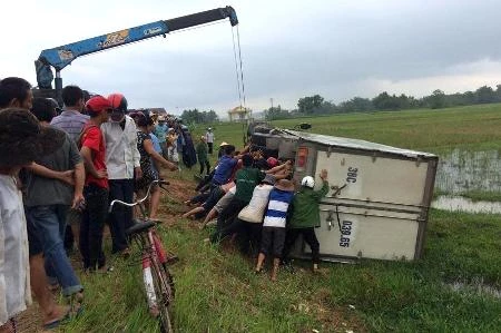 Người dân cùng cơ quan chức năng nỗ lực đưa chiếc xe lên khỏi cánh đồng