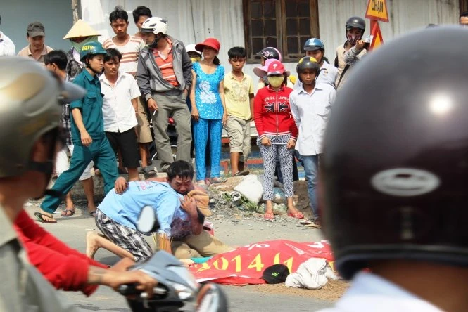 Hai cha con ôm nhau khóc bên thi thể vợ và mẹ - Ảnh: Hải Hiếu