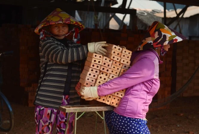 Họ giúp đỡ nhau trong việc chuyển và khuân gạch - Ảnh: Thanh Tùng