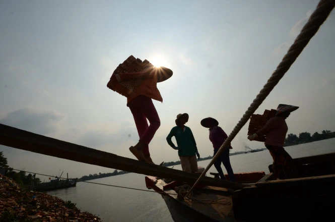 Những người phụ nữ đem số gạch xuống ghe dưới ánh nắng gay gắt -Ảnh: Thanh Tùng