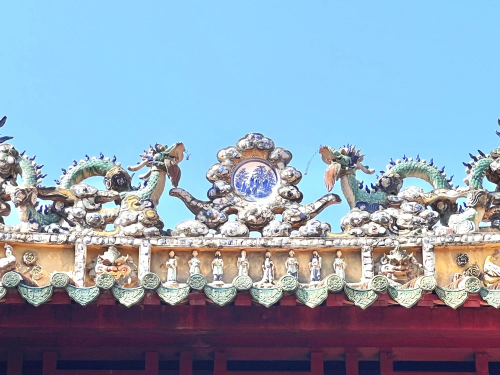 Quần thể “Lưỡng long chầu nguyệt” được trang trí trên nóc tiền điện. Ở phía giữa hai con rồng đặt một đĩa sứ mang tích truyện “Trúc lâm thất hiền” dùng để nhắc đến bảy người tài sinh sống cuối thời nhà Ngụy, đầu thời nhà Tây Tấn ở Trung Quốc, gồm: Nguyễn Tịch, Kê Khang, Lưu Linh, Hướng Tú, Nguyễn Hàm, Sơn Đào, Vương Nhung. Ảnh: QUỐC HƯƠNG.