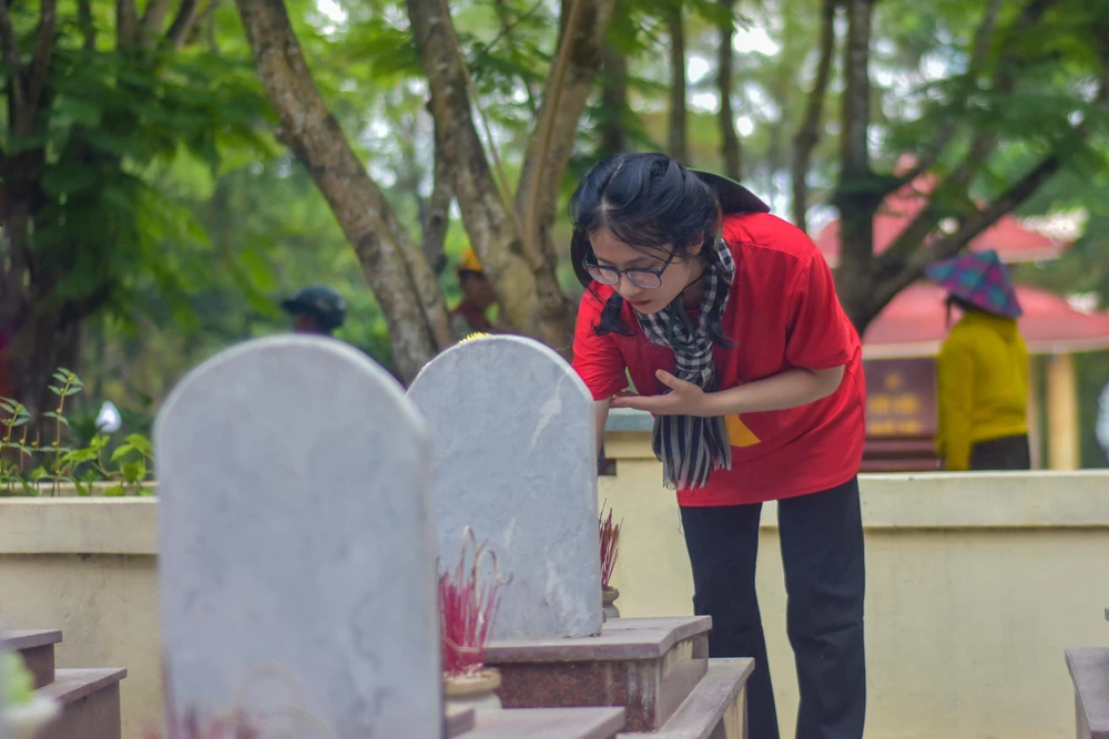 Một bạn sinh viên kính cẩn thắp hương lên mộ các liệt sĩ. Ảnh: NGUYỄN DO