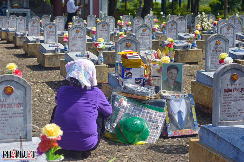Ngồi sững sờ bên nấm mộ chồng, bà Thuận kể: "Những năm trước khi sức khỏe còn tốt thì năm nào cũng vào thắp hương, nhưng mấy năm rồi sức khỏe yếu, dịch bệnh COVID-19,...mãi đến năm nay mới trở lại". Ảnh: NGUYỄN DO