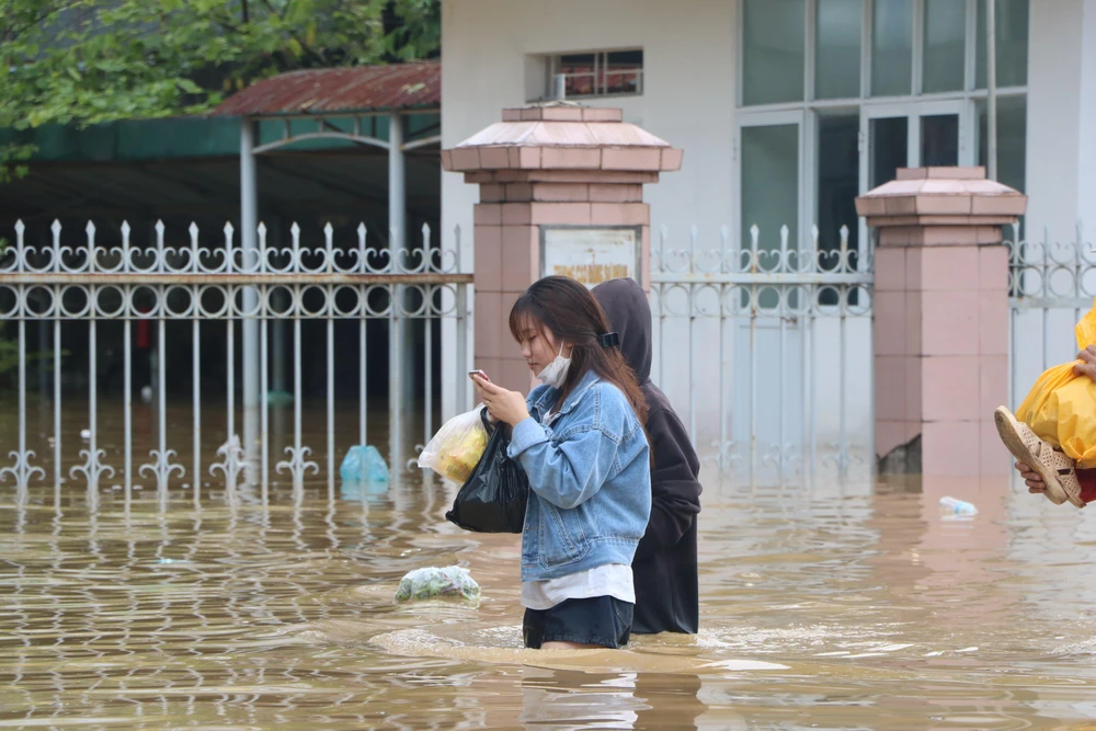 Nhiều người dân lội bì bõm trong dòng nước bạc để đi mua thức ăn.