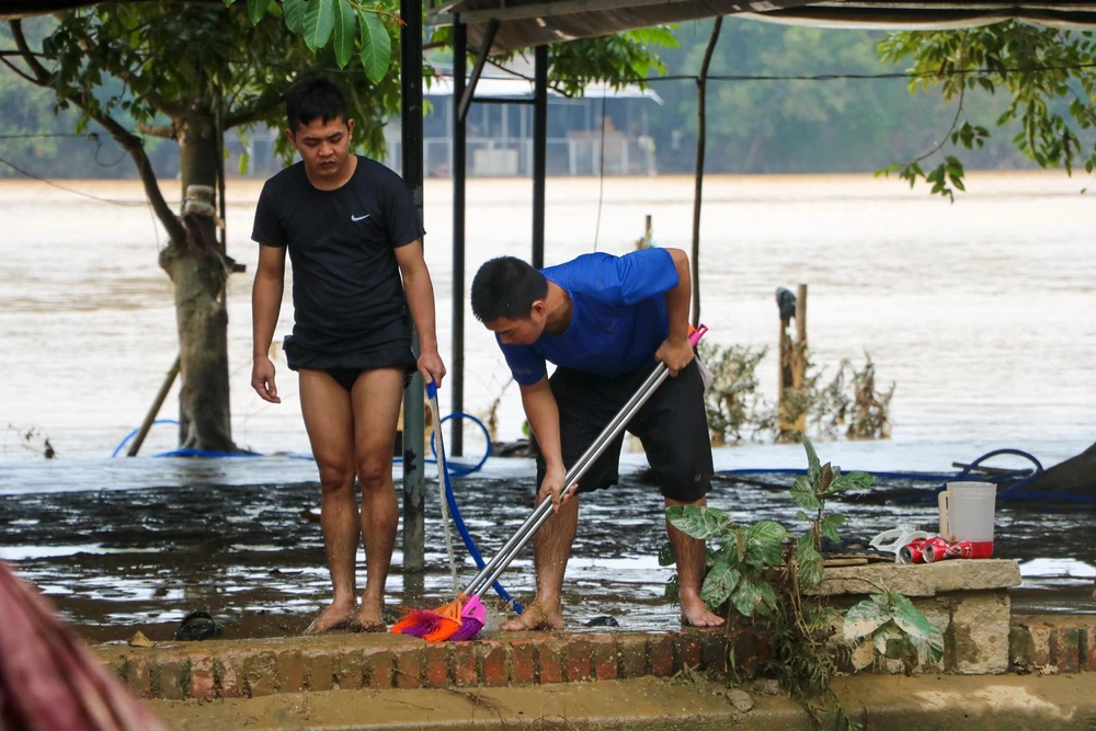 Người dân tranh thủ dọn dẹp lớp bùn đất. Với lớp bùn non này, khi nước vừa rút người dân sử dụng các vật dụng để quét dọn, tránh để bùn đông cứng lại, khó dọn.