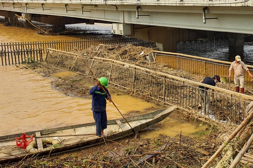 Rác thải chất đầy trên cầu gỗ lim, các công nhân vất vả xử lý.