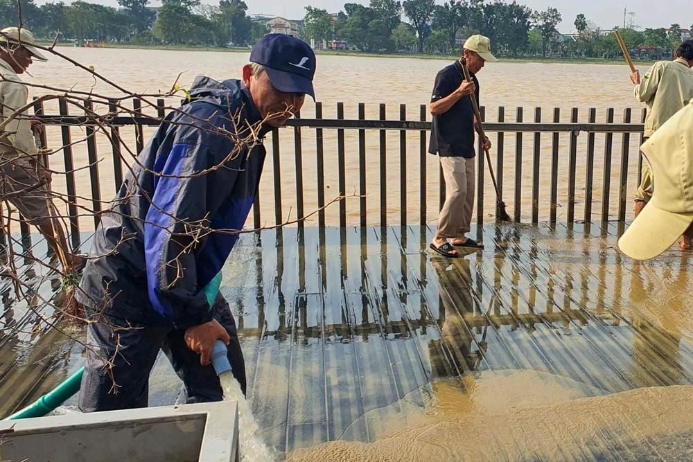 Công nhân dùng nước xịt bùn đất bám trên mặt cầu.