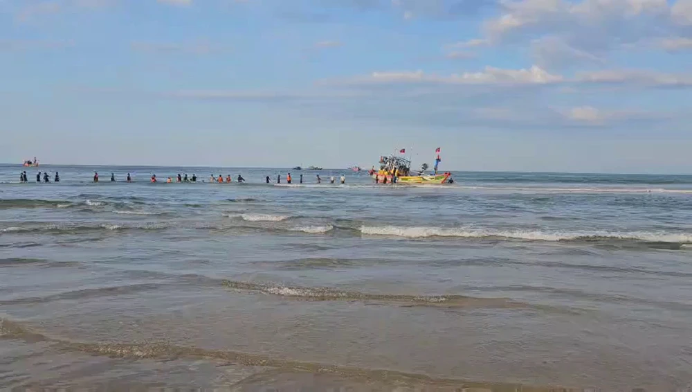 Lực lượng chức năng và người dân kéo tàu cá ra khỏi vị trí mắc cạn.