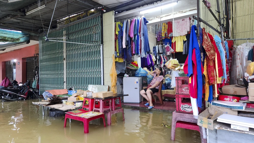 Bà Lê Thị Mộng thẫn thờ ngồi nhìn nước lũ dâng cao từng phút. Ảnh: NGUYỄN DO