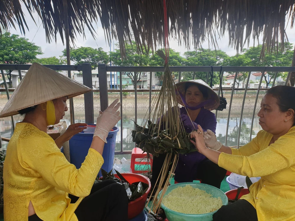 Chị Hà (trái) cùng các chị em trong khu phố gói bánh ú lá tre tại lễ khai mạc Tuần lễ trái cây. Ảnh: VĂN HÀ.