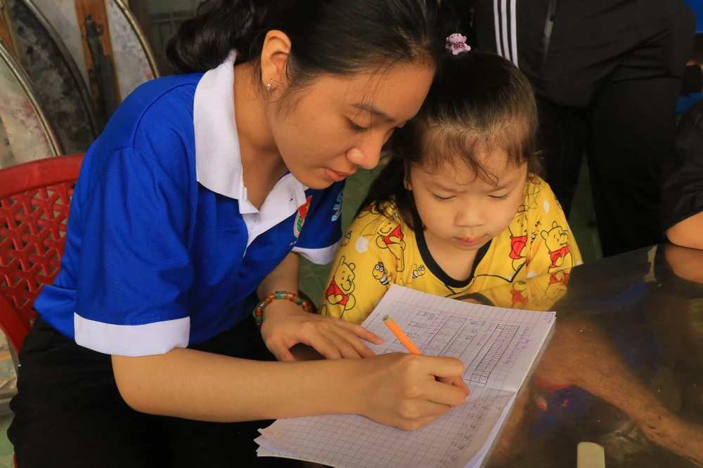 Tuyết Mai ân cần trong giờ tập viết cùng một em bé. Ảnh: VÕ THƠ