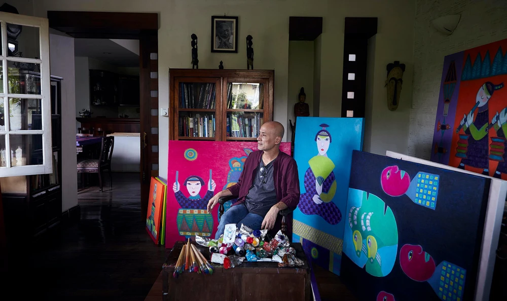 Hoạ sĩ Hoàng Phượng Vỹ bên cạnh các tác phẩm của mình. Ảnh: NVCC