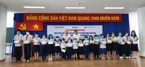 TBT báo SGGP Tăng Hữu Phong và ông Trần Phước Sang, Phó trưởng VPĐD Agribank khu vực miền Nam, trao học bổng cho các em.