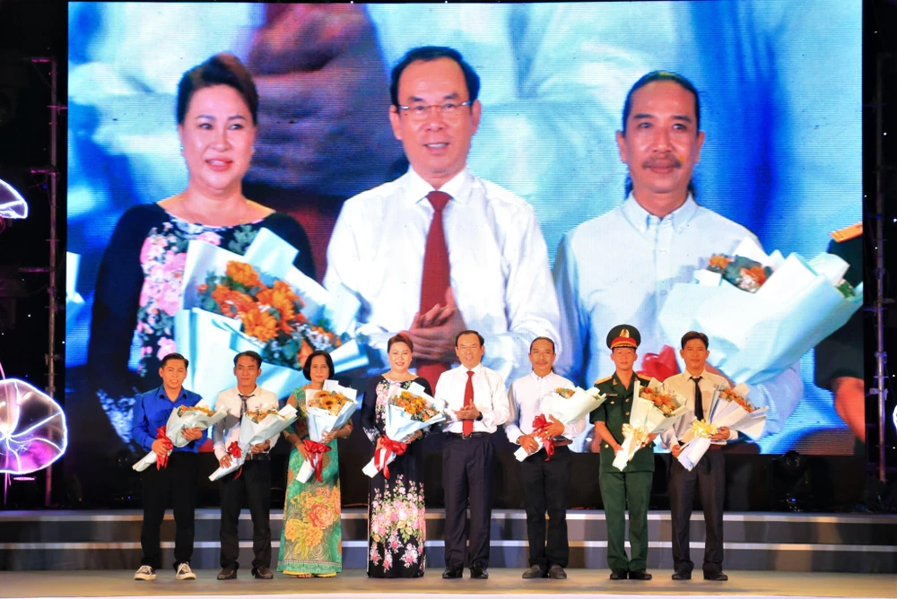Ông Nguyễn Văn Nên, Bí thư thành ủy TP.HCM tặng hoa cho bác sĩ Phạm Thị Ngọc Dung (giữa) và các tấm gương giao lưu tại Lễ tuyên dương.