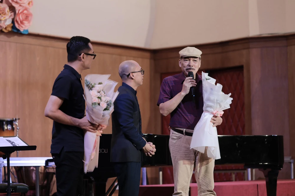 Nhạc trưởng Huỳnh Quang Thái (giữa) tặng hoa chúc mừng nhạc sĩ Trần Tiến. Ảnh: THANH HÙNG