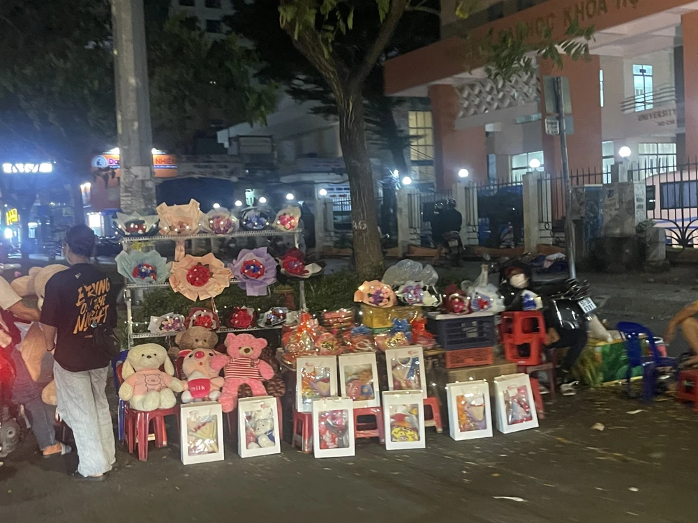 Dù đã tối muộn, sạp hoa, quà tặng trên đường Nguyễn Văn Cừ vẫn còn rất nhiều hàng chưa bán hết. Ảnh: THUỶ TÂM.