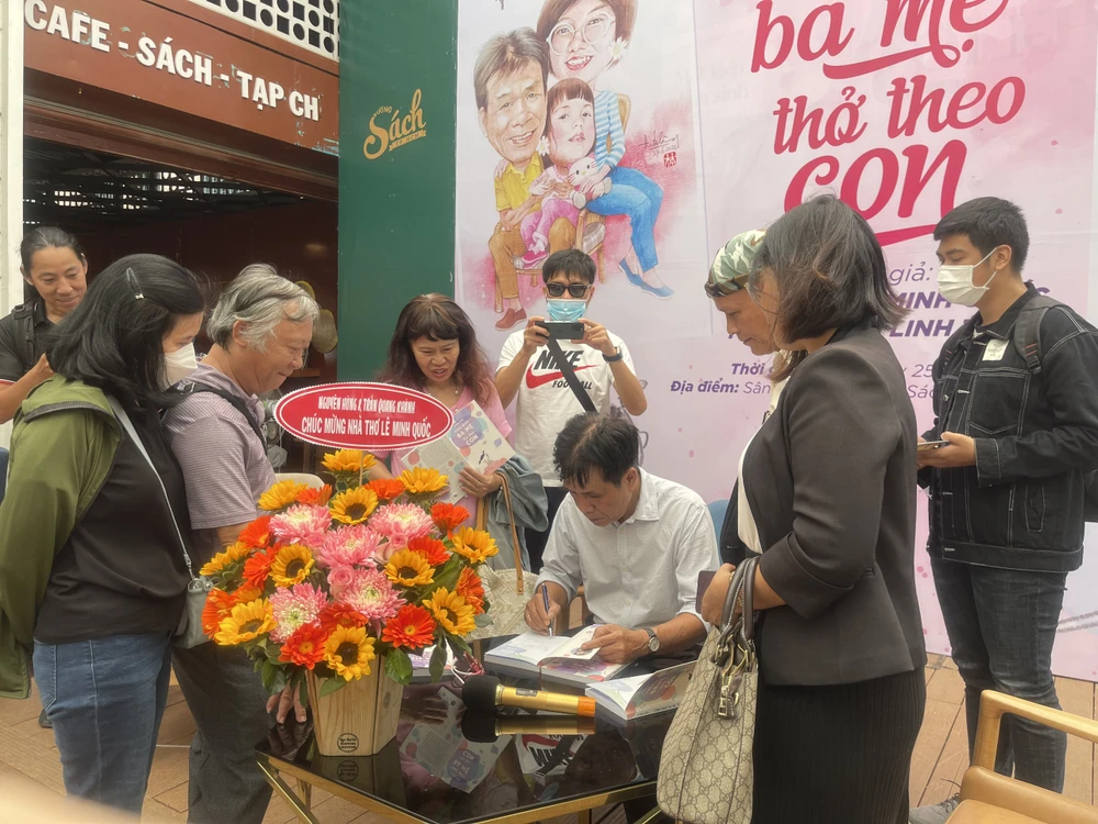 Nhà thơ Lê Minh Quốc ký tặng sách cho độc giả. Ảnh: THUỶ TÂM