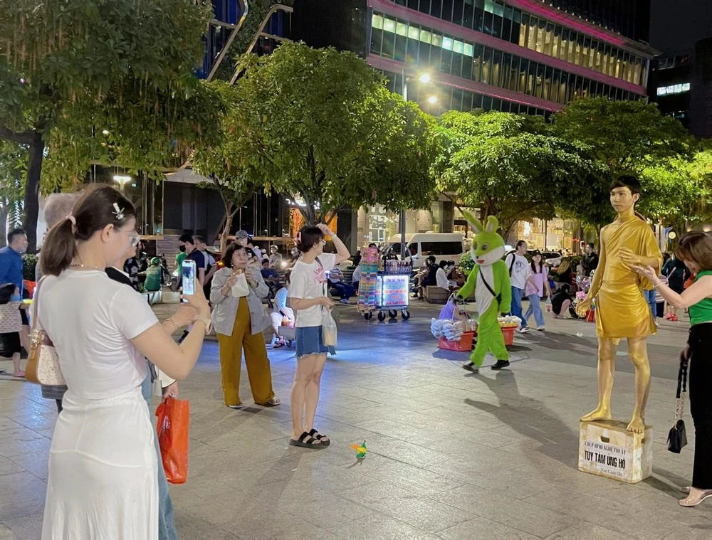 Du khách hào hứng chụp hình cùng nhân tượng tại Phố đi bộ Nguyễn Huệ. Ảnh: KHÁNH TRÚC