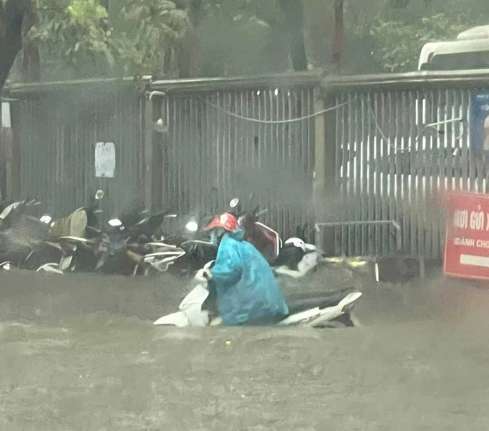 Xe máy ngập qua nửa thân xe, người dân phải dẫn bộ trong biển nước ở đường Phạm Văn Bạch. Ảnh: CTV