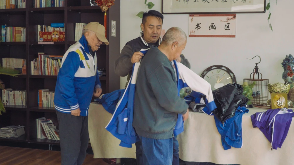 Feng Yan (giữa) giúp cư dân Jingya mặc đồng phục trước khi quay video ngắn. Ảnh: Ding Rui/Sixth Tone