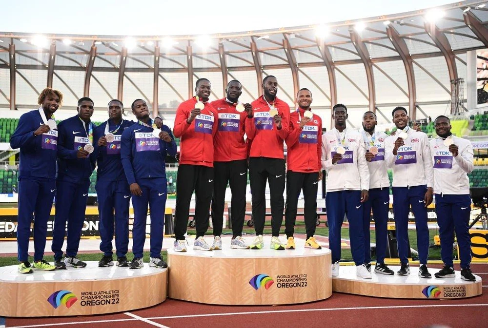 Đội tuyển điền kinh Mỹ (trái) trên bục nhận huy chương cự ly 4x100 m tiếp sức. Ảnh: GETTY