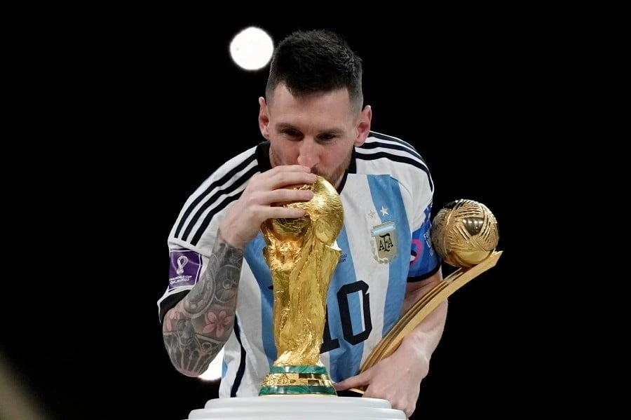 Messi tay cầm danh hiệu Cầu thủ xuất sắc nhất tự hào hôn lên chiếc cúp vô địch World Cup 2022. Ảnh: AP