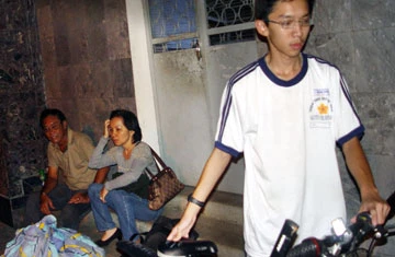 Một gia đình ở lầu hai sát nơi lún vừa gom được túi xách vở và chiếc xe đạp cho con đi học. Ảnh: HTD