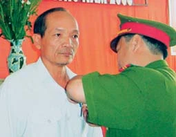 Đại tá Phạm Ngọc Hiền gắn kỷ niệm chương cho họa sĩ Võ Tấn Thành.