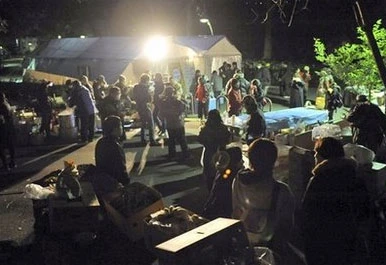 Mọi người ăn cháo bên ngoài làng tạm dịp năm mới. Ảnh AP