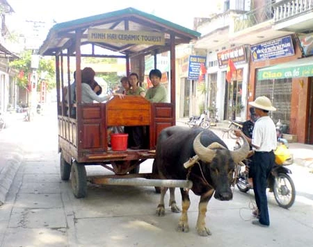 Mô hình dịch vụ “xe trâu” tại làng Gốm Bát Tràng thu hút khách du lịch (Ảnh: C. Hà).