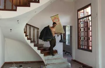 Một người khuân vác những vật dụng cuối cùng từ lầu hai xuống. Ảnh: TẤN VŨ Một người khuân vác những vật dụng cuối cùng từ lầu hai xuống. Ảnh: TẤN VŨ