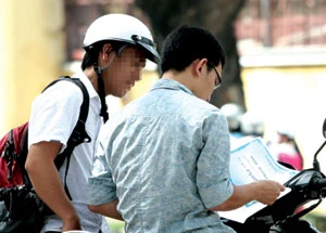 Phóng viên đang xem giấy chứng nhận các suất học bổng của “cò” Thành (đội mũ bảo hiểm). Ảnh: Lê Hồng Thái