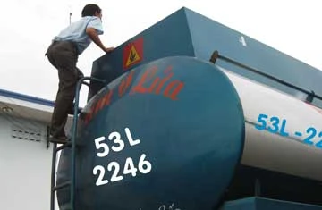 Nhân viên thu phí leo lên xe bồn để kiểm tra trọng lượng bằng... mắt.