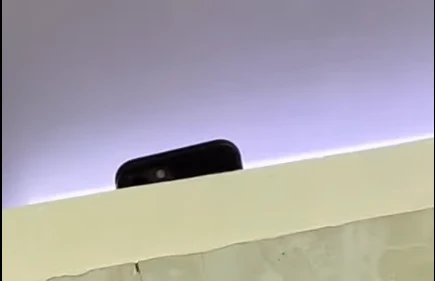 Chiếc điện thoại đang thực hiện quay lén được nam sinh quay lại khi vào nhà vệ sinh. Ảnh cắt từ clip