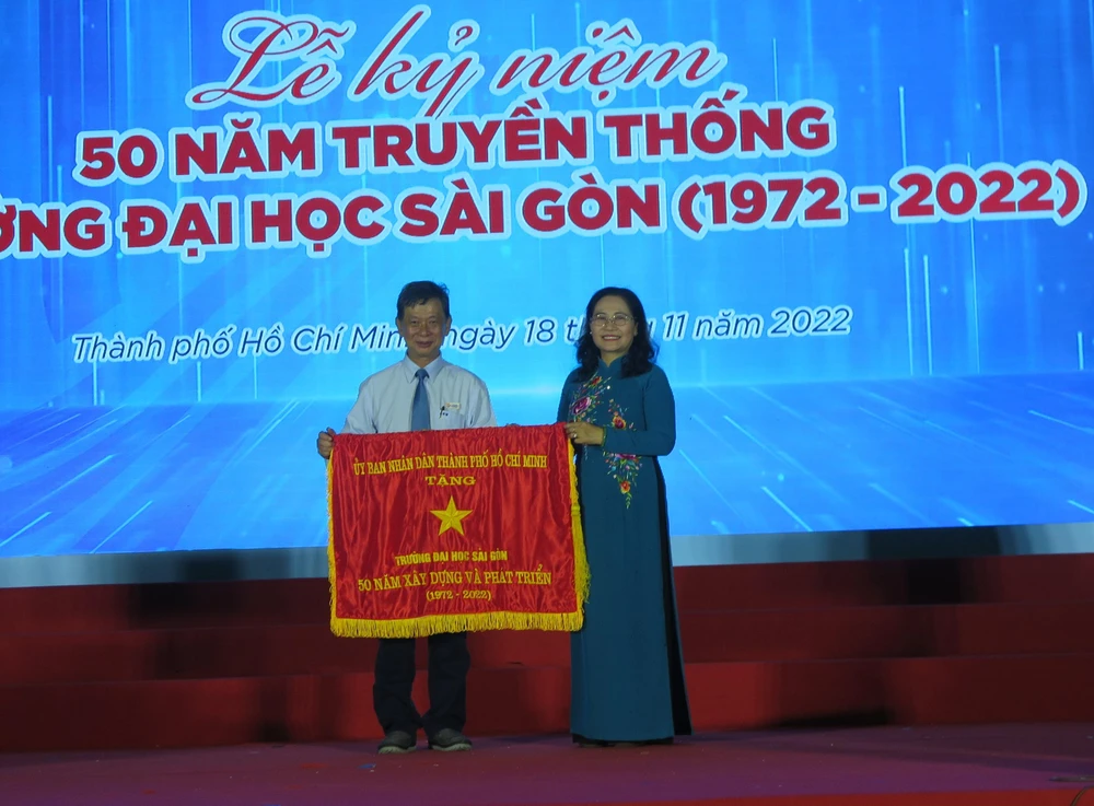 Phó Bí thư Thành ủy Nguyễn Thị Lệ tặng cờ thi đua cho Hiệu trưởng Phạm Hoàng Quân - đại diện tập thể trường. Ảnh: PA