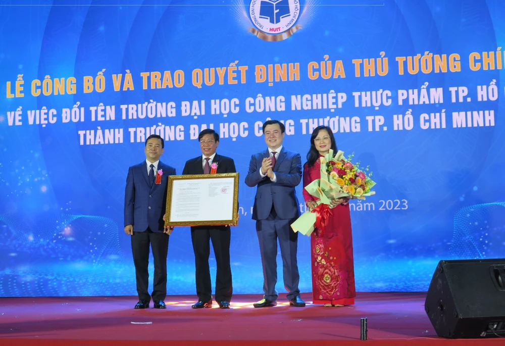 Thứ trưởng Bộ Công Thương, ông Nguyễn Sinh Nhật Tân (thứ hai từ trái qua) trao quyết định đổi tên trường cho ban lãnh đạo trường. Ảnh: P.ANH