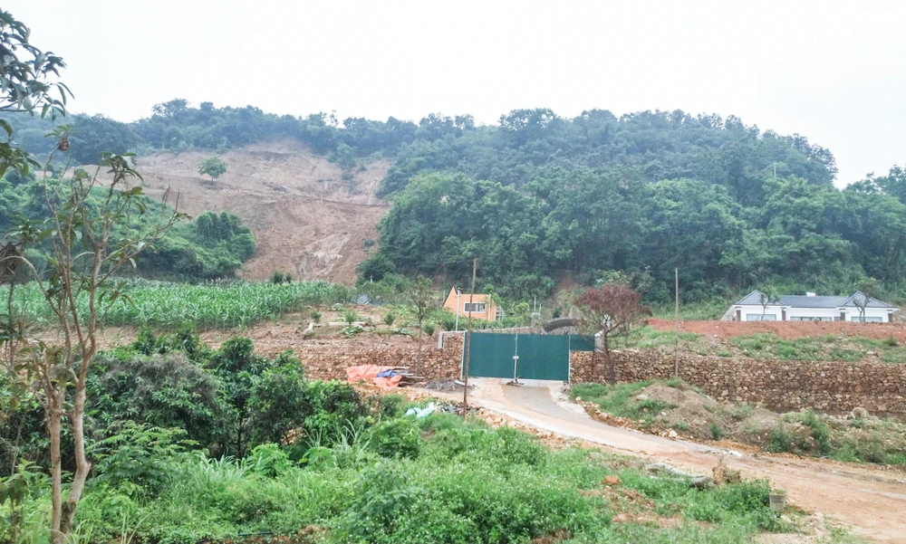 Nhìn từ xa, có thể dễ dàng trông thấy khu vực hiện trường vụ sạt lở đất đá, sập tường nhà khiến 3 người tử vong và một người bị thương đã bị tác động bởi máy móc.