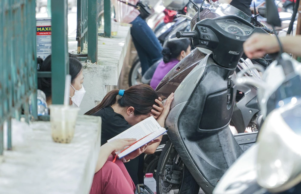 Dưới thời tiết oi bức của mùa hè, một số người tranh thủ chợp mắt trong lúc chờ đợi con em mình.